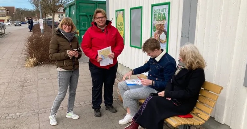 En grupp människor som sitter på en träbänk.