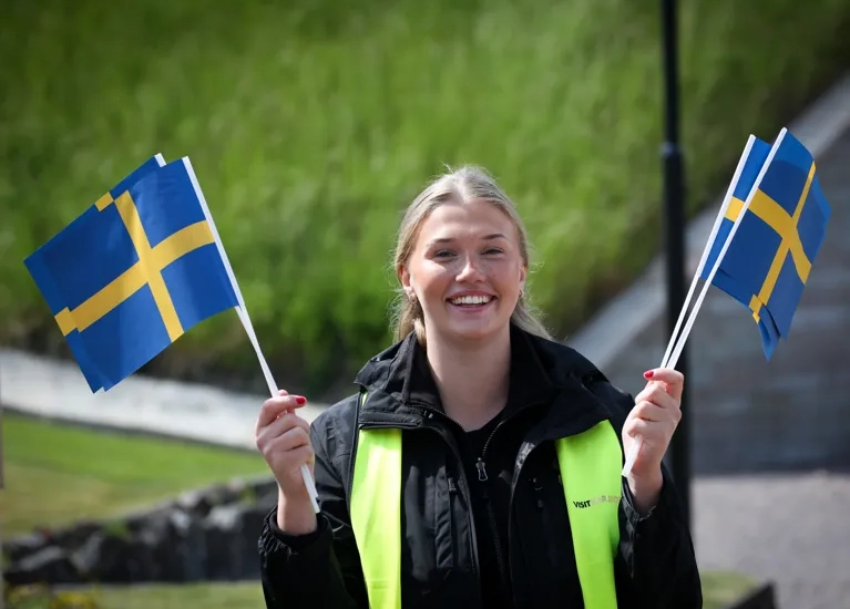 En kvinna håller två svenska och svenska flaggor.