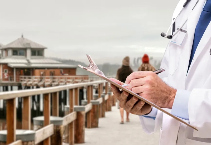 En man i vit labbrock skriver på en skrivplatta.