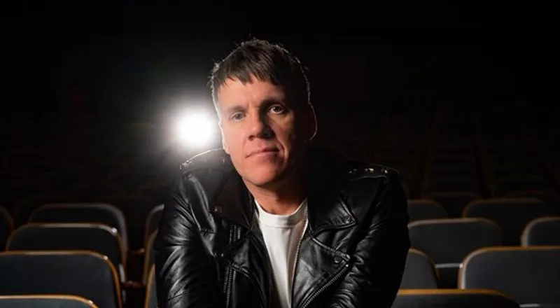 En man i svart jacka sitter på en teater.