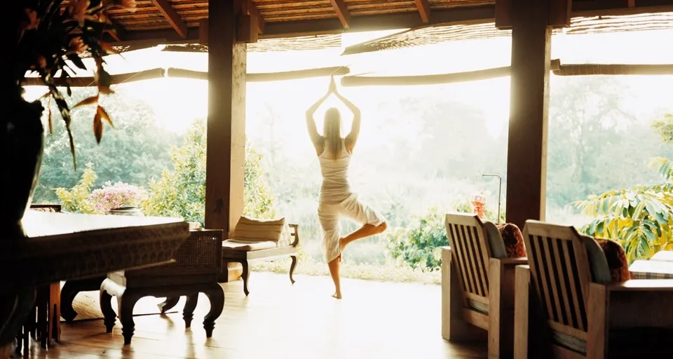 En kvinna gör en yogaposition i ett vardagsrum.