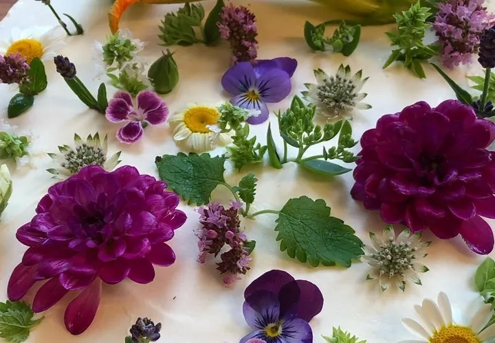 En tårta dekorerad med blommor på ett träbord.
