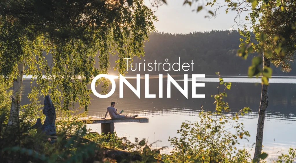 En man sitter på en båt på en sjö.