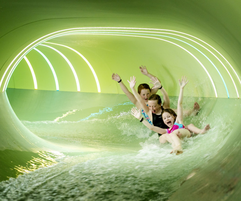 A family rides a green water slide.