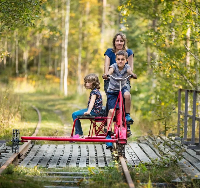 Kvinna och två barn cyklar dressin.