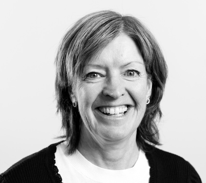 A black and white picture with a smiling woman with dark short hair.