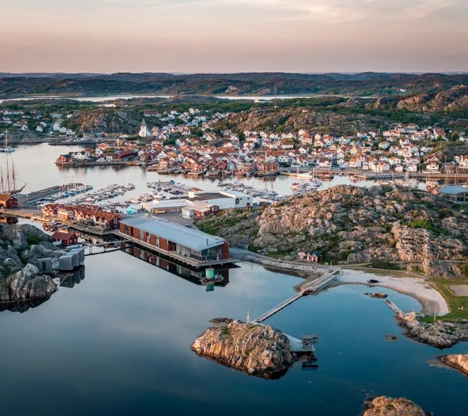 Flygbild över kustsamhälle i kvällssol.