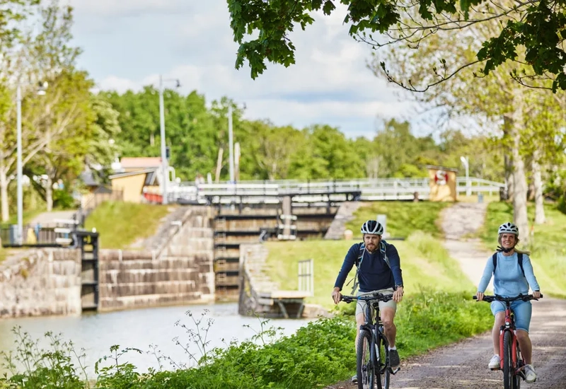 A couple of people riding bikes down a dirt road.