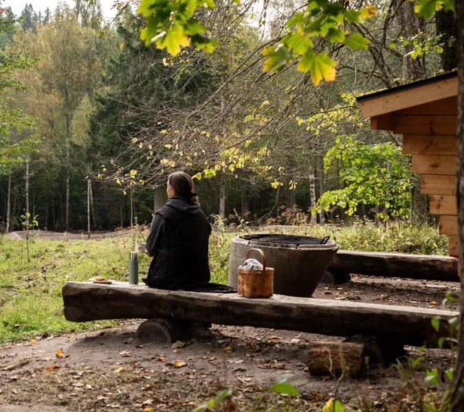 Ein Mann sitzt auf einer Bank neben einem Baum.