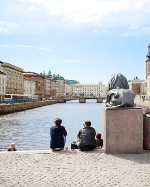 Några personer som sitter bredvid ett vattendrag.