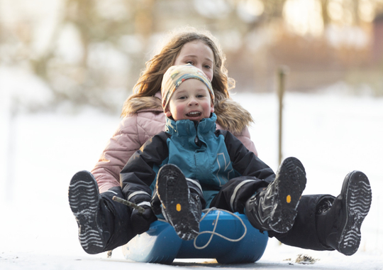 Två barn leker i snön.