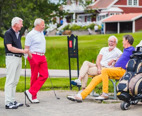 A group of people sitting on a bench near a golf bag.