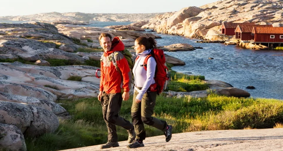 Man och kvinna promenerar längs med vatten och klippor