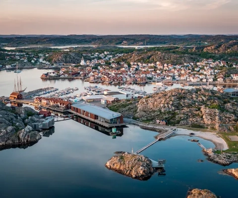 Flygbild över kustsamhälle i kvällssol.