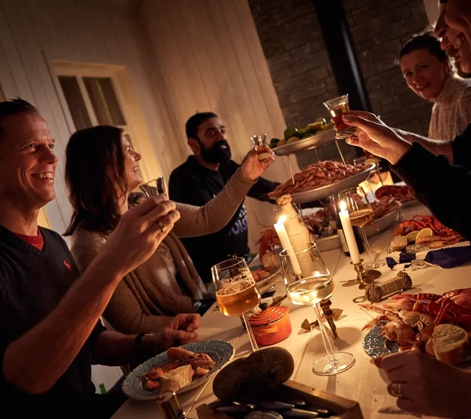 En grupp människor som sitter runt ett bord med skaldjur och dryck.