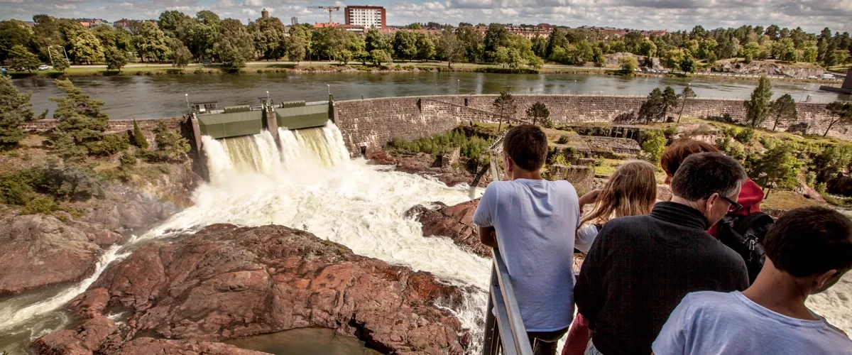 En grupp människor som står på en bro och tittar på ett vattenfall.