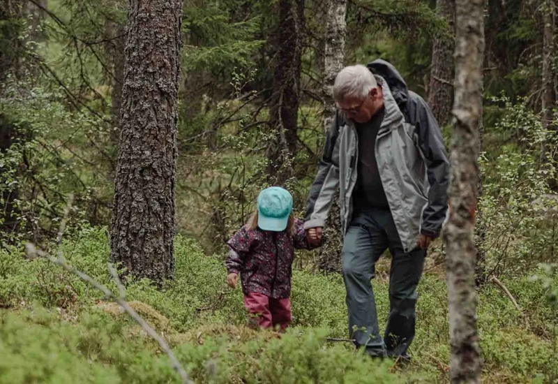 A man and a child walking through a forest.