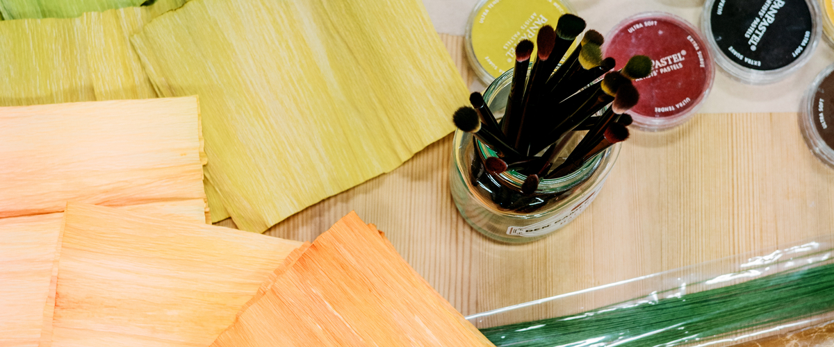 Bild på bord med papper, färg och penslar.