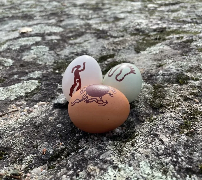 Tre ägg med mönster på som sitter på en sten.