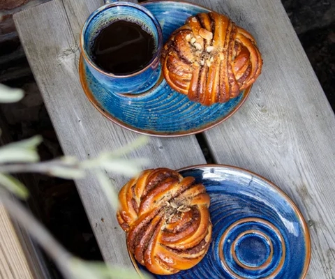 Blå fat med bullar och en blå kaffekopp med kaffe i.