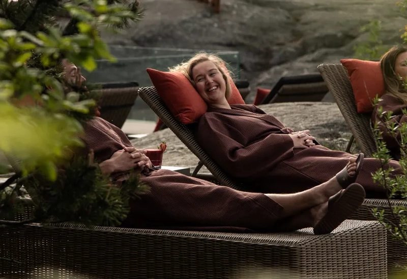 A woman laying on top of a couch next to a tree.