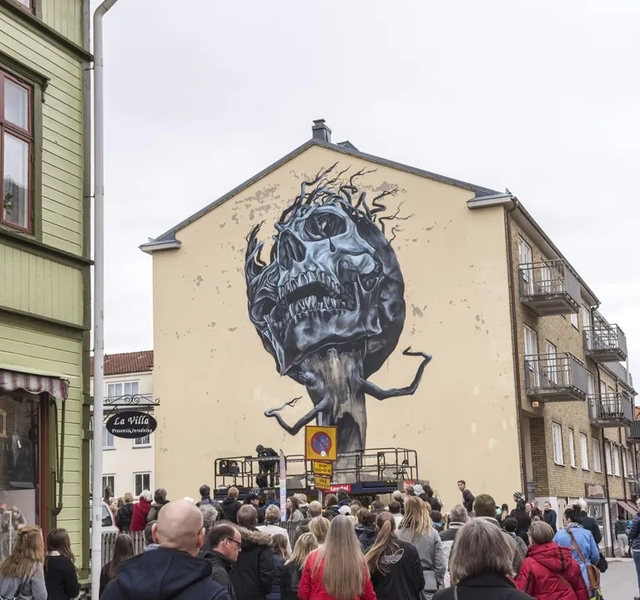 En folkmassa som går längs en gata bredvid höga byggnader.