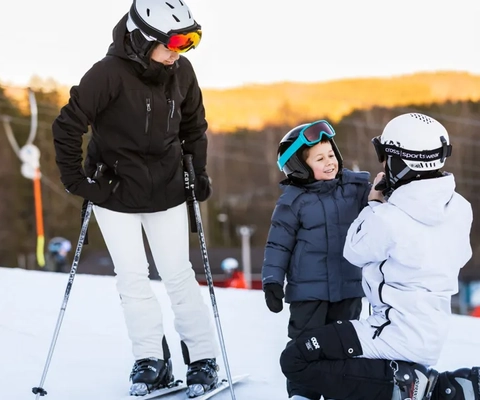 En grupp människor som åker skidor på toppen av en snötäckt sluttning.