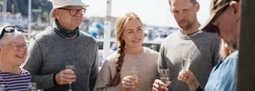 En grupp människor som står runt ett bord med glas.