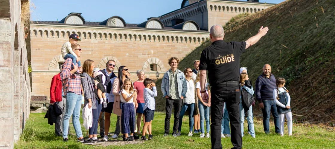 En grupp människor som står på ett fält bredvid en byggnad.