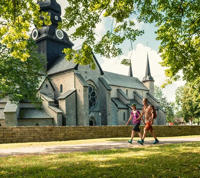 Pilgrimsvandrare framför stor kyrka.