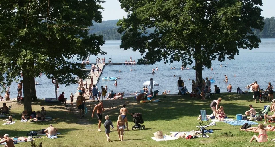 En stor grupp människor som njuter av en dag vid sjön.