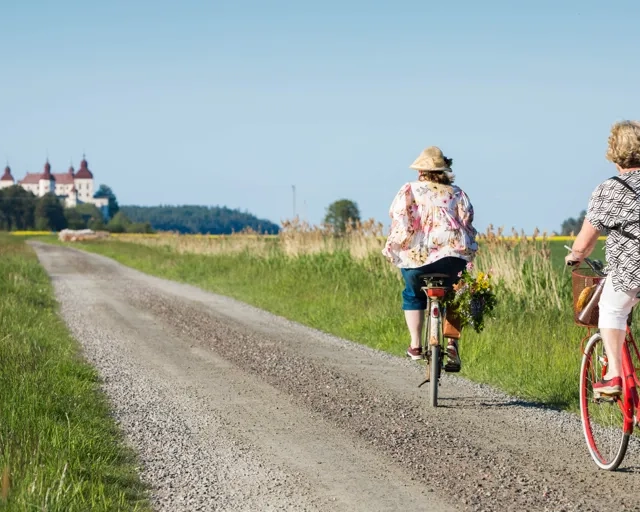 Några personer som cyklar på en grusväg mot Läckö slott
