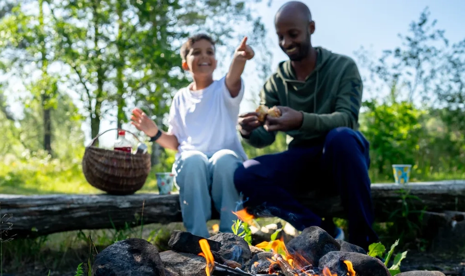 En pappa och ett barn grillar marshmallows över öppen eld.