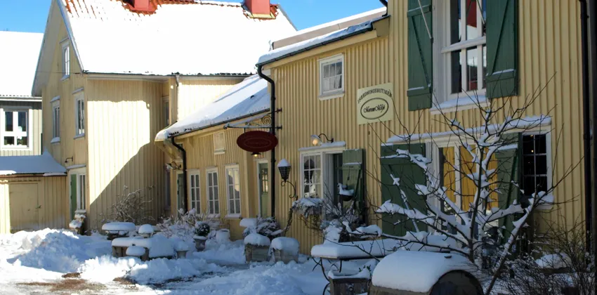 En gul byggnad med gröna fönsterluckor täckt av snö.