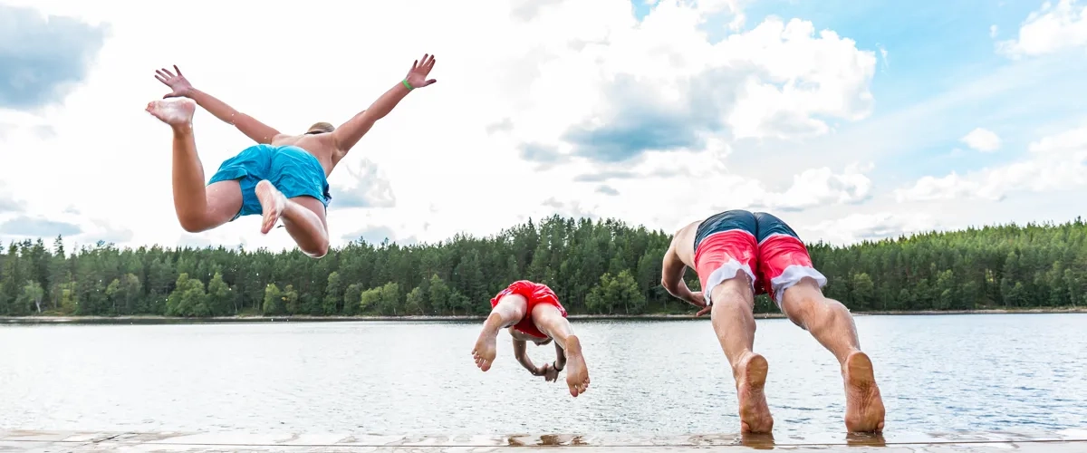 Tre pojkar som dyker från en brygga i Lilla Havsjön som finns på Hökensås naturområde utanför Tidaholm.