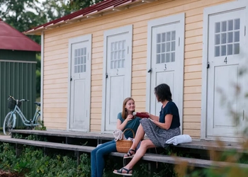 Two women sitting on a bench in front of a building.