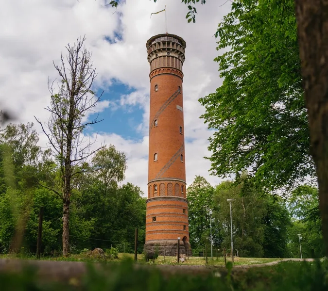 Utsiktstorn i rött tegel med träd och buskar runt omkring.