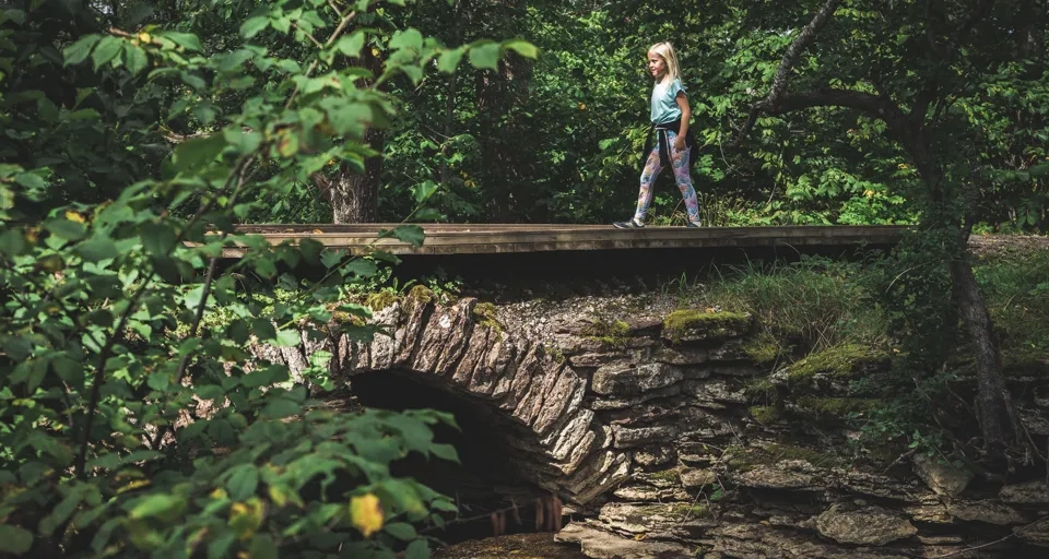 Flicka går över en stenbro på Rosenstigen vid Varnhem