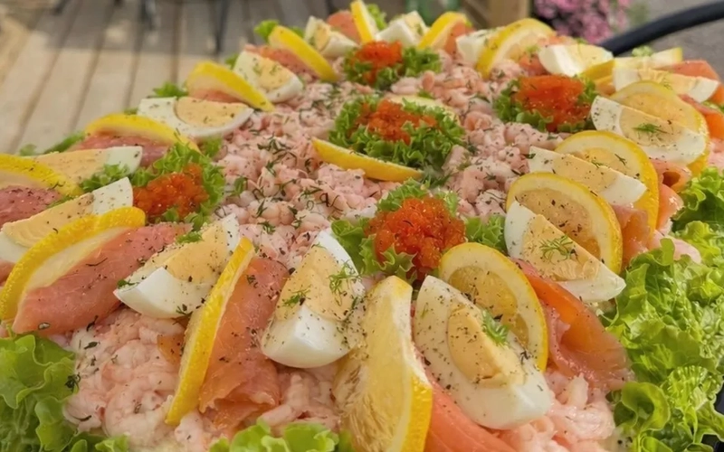 Ett fat med mat på ett bord med ett paraply i bakgrunden.