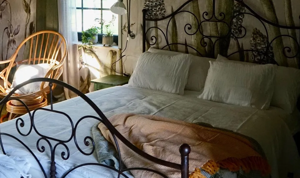 Ett sovrum med en prydligt bäddad säng och en stol.