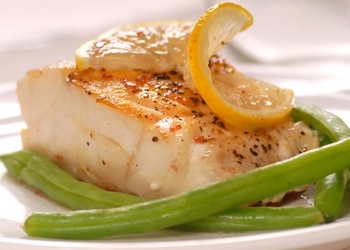 Fisk med grönsaker på en vit tallrik.