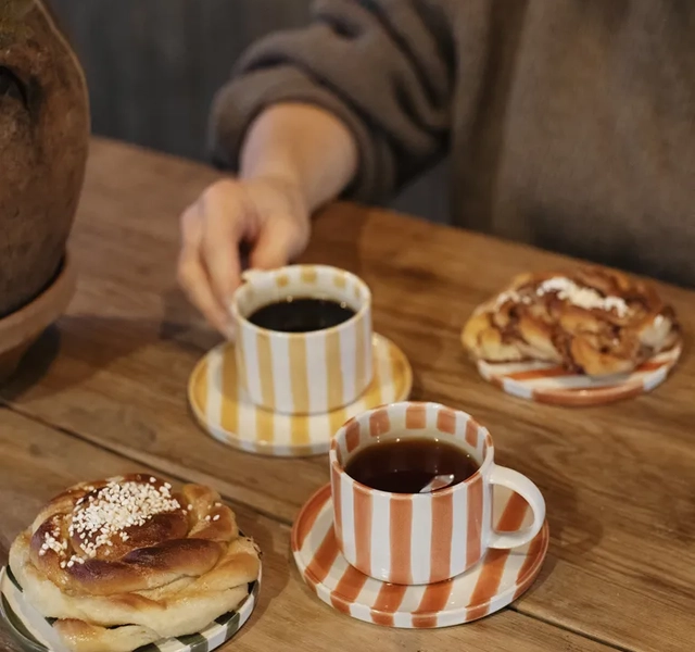Två randiga kaffekoppar och två fat med bullar.
