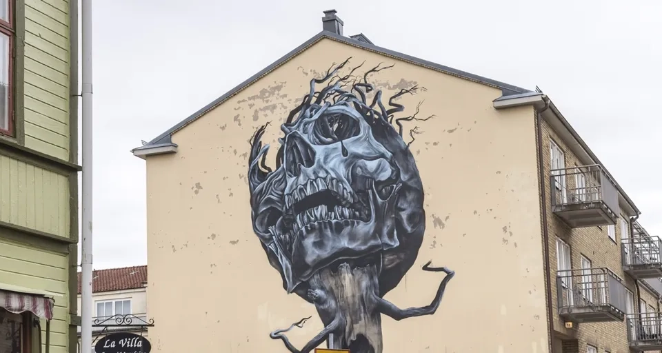 En folkmassa som går längs en gata bredvid höga byggnader.