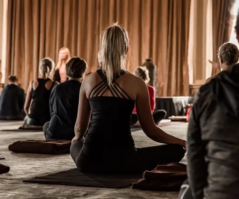 En gruppe mennesker som gjør yoga i et rom.