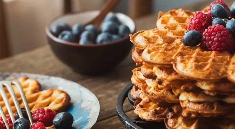 A stack of waffles topped with berries and blueberries.