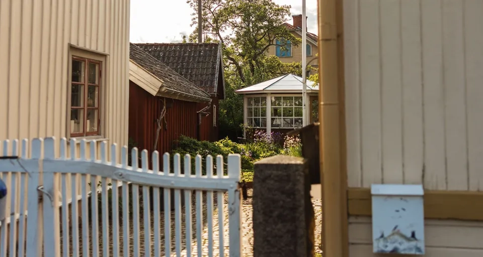 Ein weißer Lattenzaun vor einem Haus.