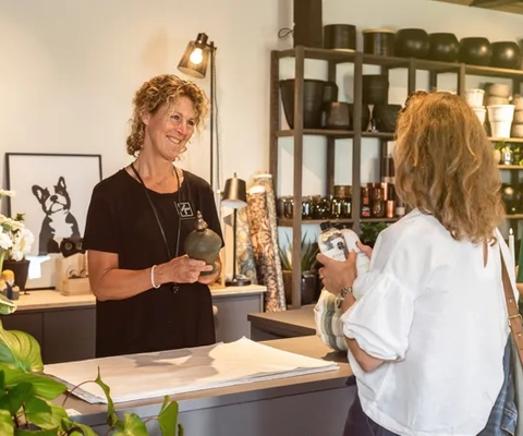 Två kvinnor som handlar inredning av butiksinnehavaren.