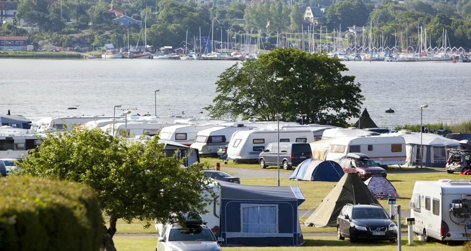 Många parkerade husbilar nära ett vattendrag.