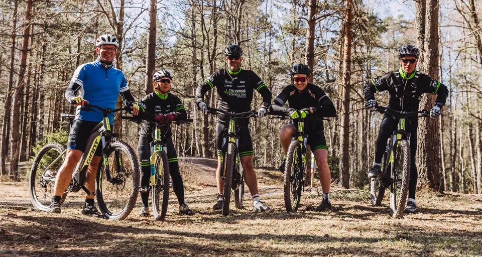 Fem stycken mtb-cyklister står uppradade i skogen och tittar in i kameran.