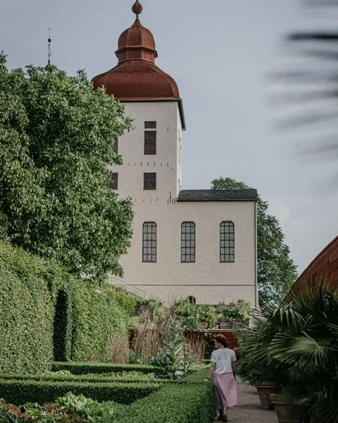Kvinna strosar i Lilla Slotsträdgården vid Läckö Slott